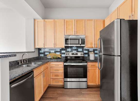 A kitchen with wooden cabinets and a black refrigerator.