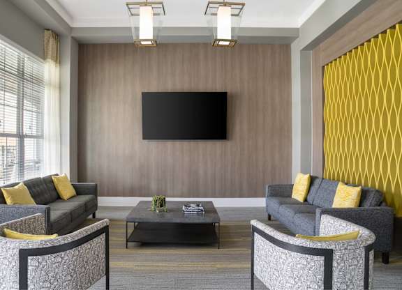 A modern living room with grey sofas and a black television.