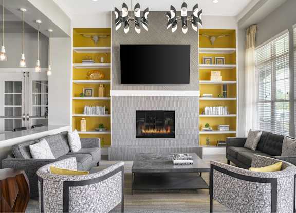 A modern living room with a grey fireplace and a television mounted above it.