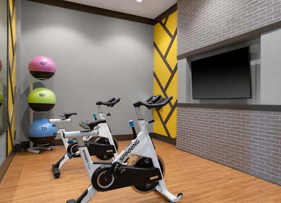A Spinning bike is in the foreground of a brightly colored gym.