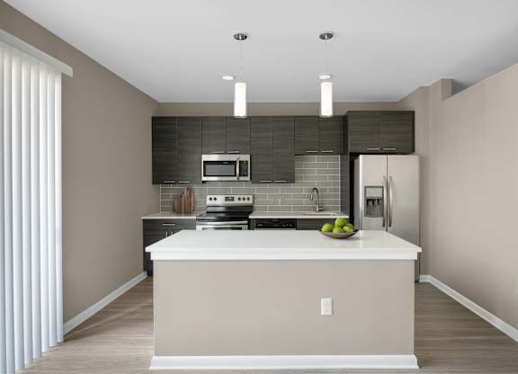 A modern kitchen with a white island and stainless steel appliances.