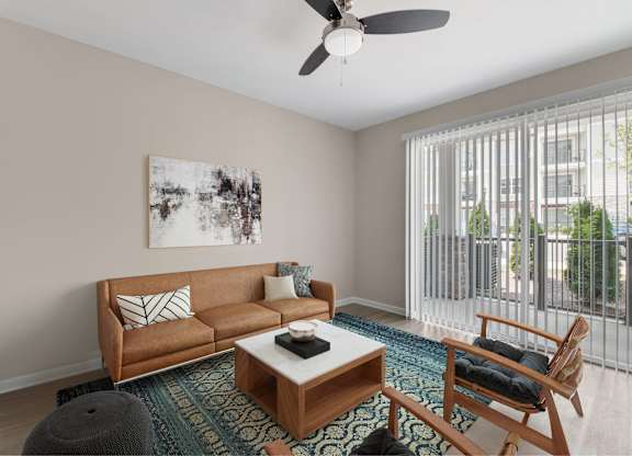 A living room with a brown couch, a coffee table, and a ceiling fan.