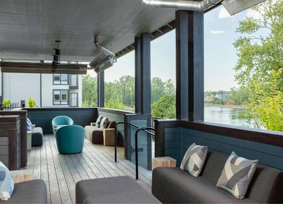 A patio with a couch and chairs overlooking a body of water.