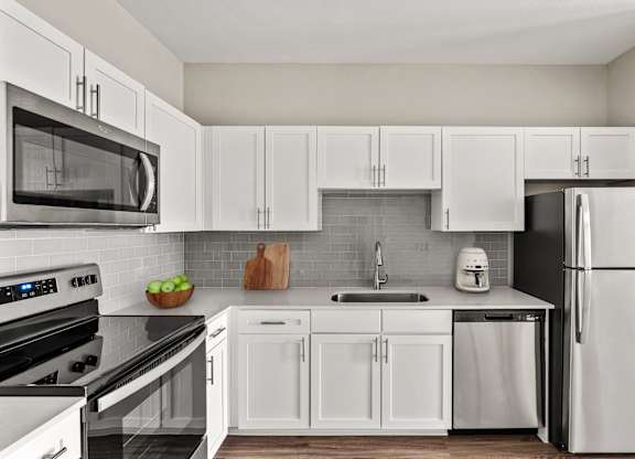 A modern kitchen with white cabinets and appliances.