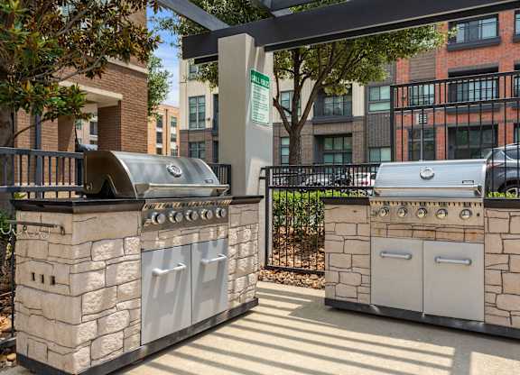 Two stone BBQs are in a sunny courtyard.