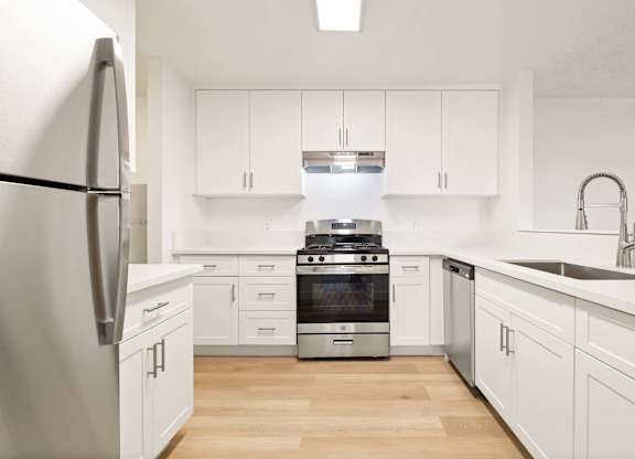 A modern kitchen with white cabinets and stainless steel appliances.