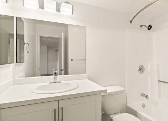 A white bathroom with a sink, toilet, and shower.