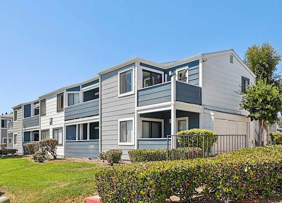 A grey and white building with a green lawn in front.