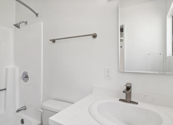 A white bathroom with a toilet, sink, and mirror.
