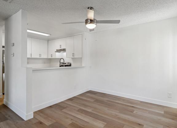 A kitchen area with a fan and wooden floors.
