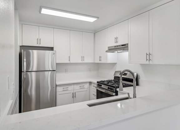 A modern kitchen with white cabinets and stainless steel appliances.