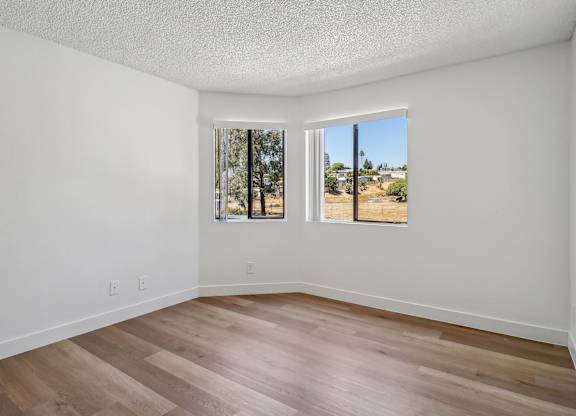 A room with two windows and wooden flooring.