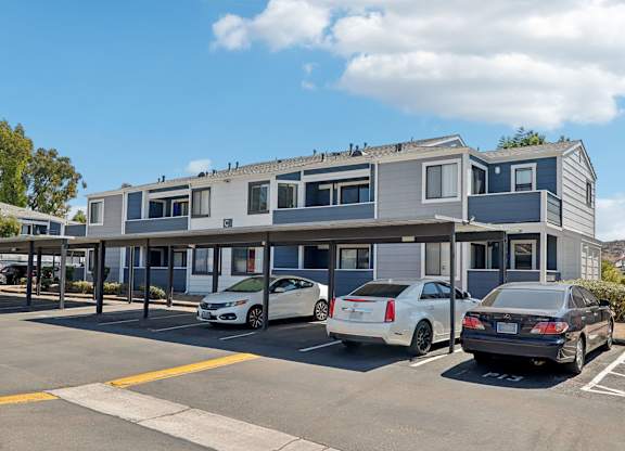 A parking lot with three cars parked in front of a building.