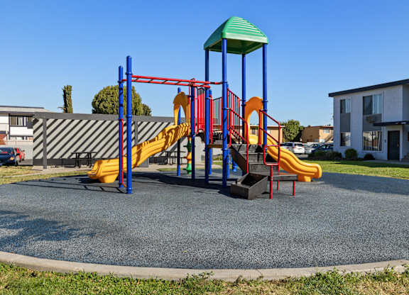 A playground with a yellow slide and a green roof.