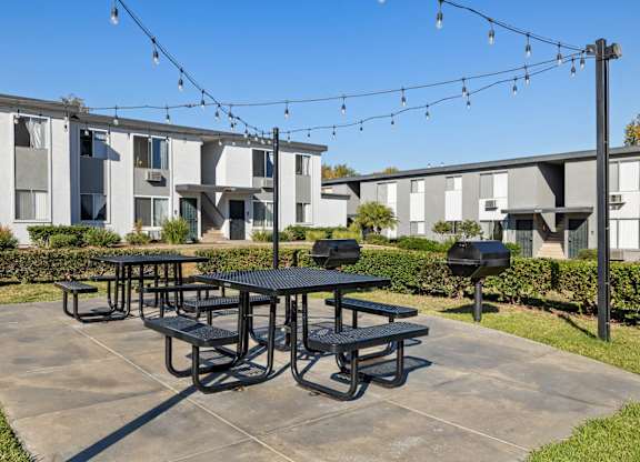 A black picnic table is in the middle of a concrete patio.