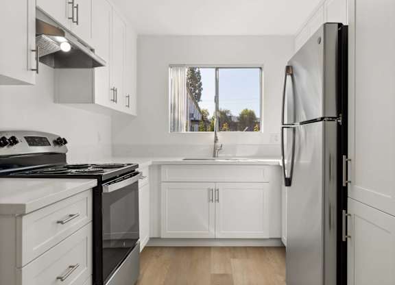 A modern kitchen with white cabinets and a black refrigerator.