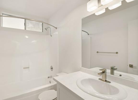 A white bathroom with a tub, toilet, and sink.