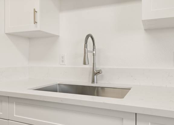 A modern kitchen with a white sink and faucet.