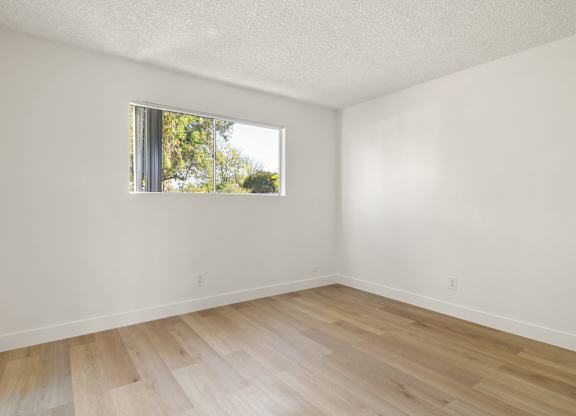 A room with a window and wooden flooring.