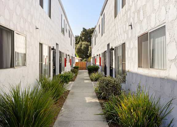 A white building with a patterned wall and a red door.