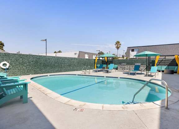 A small pool with a metal railing and a few chairs around it.