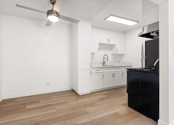 A kitchen with white cabinets and a black counter.