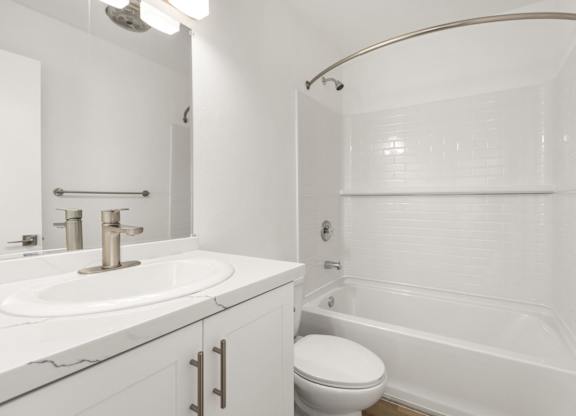 A white bathroom with a sink, toilet, and bathtub.