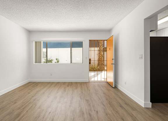 A room with a wooden floor and a door leading to a balcony.