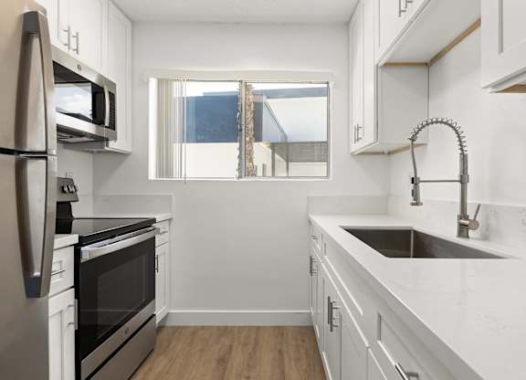 A modern kitchen with white cabinets and stainless steel appliances.