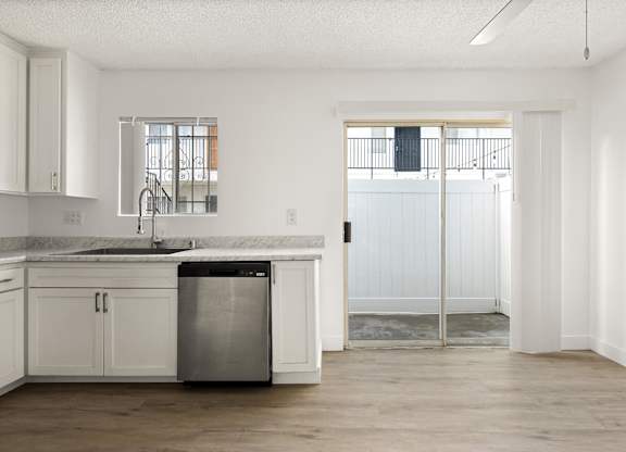 A kitchen with white cabinets and a marble countertop.