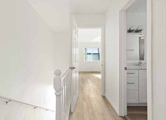A white hallway leads to a kitchen.