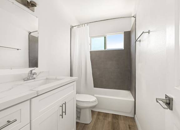 A white bathroom with a toilet, sink, and shower.