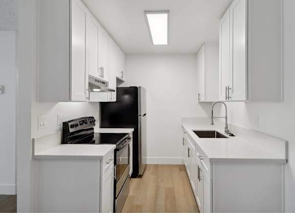 A kitchen with black appliances and white cabinets.