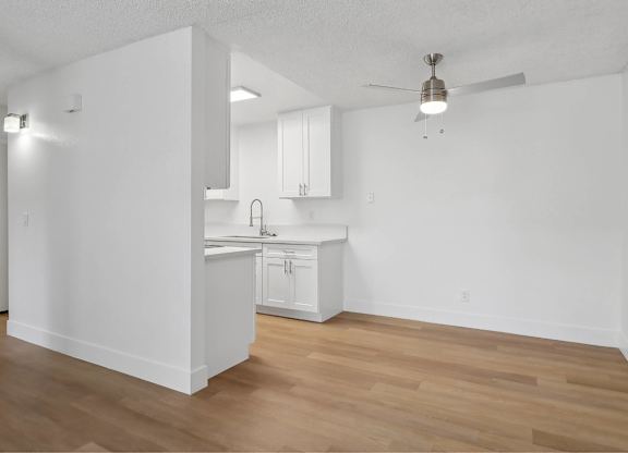 A kitchen with white cabinets and a wooden floor.