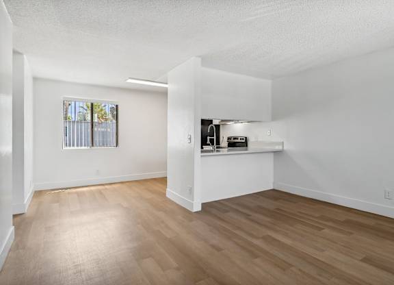 A room with wooden flooring and a window with blinds.