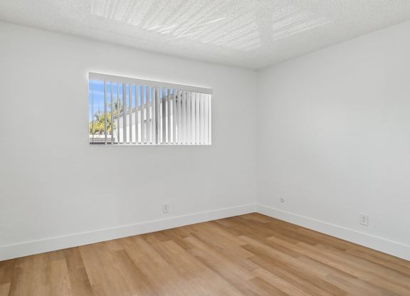 A room with a window and wooden flooring.