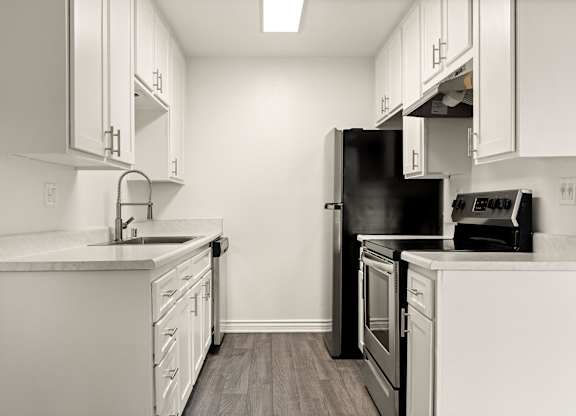 A kitchen with white cabinets and a black refrigerator.