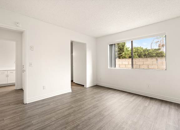 A room with a large window and wooden flooring.