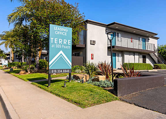 A leasing office sign for 989 Peach stands in front of a building.