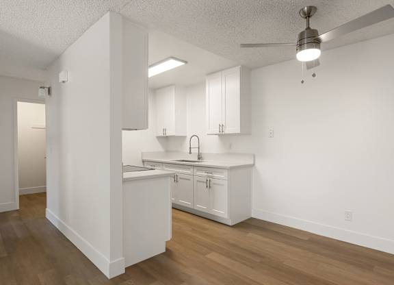 A kitchen with white cabinets and a wooden floor.