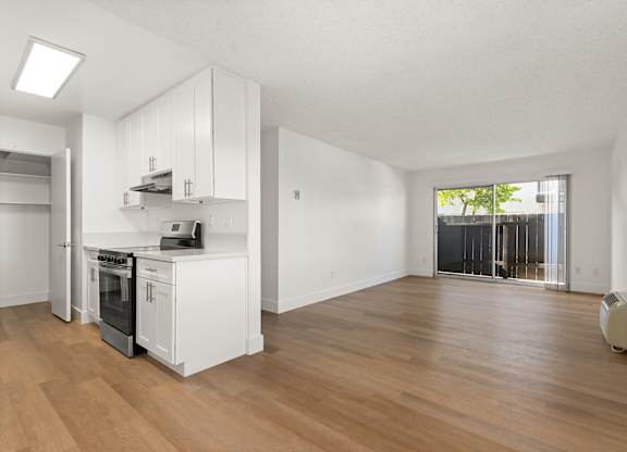 A kitchen with white cabinets and a wooden floor.