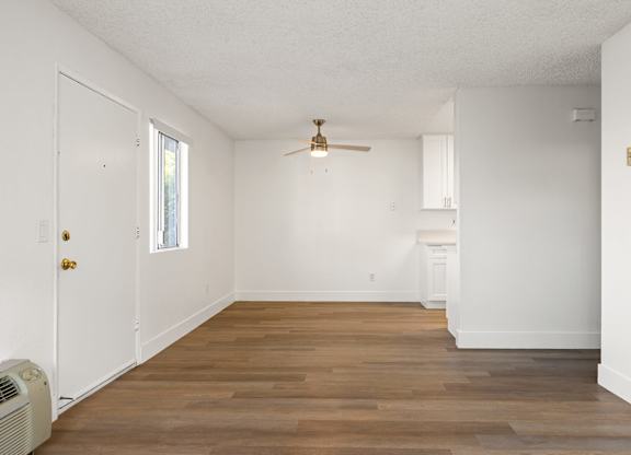 A room with a ceiling fan and wooden flooring.