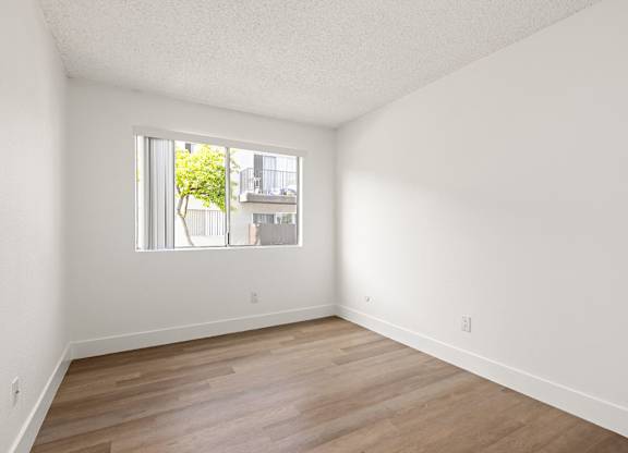 Empty room with a window and wooden flooring.