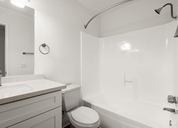 A white bathroom with a toilet, sink, and bathtub.