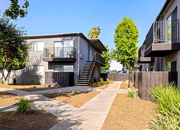A modern apartment complex with a well-maintained garden and pathway.