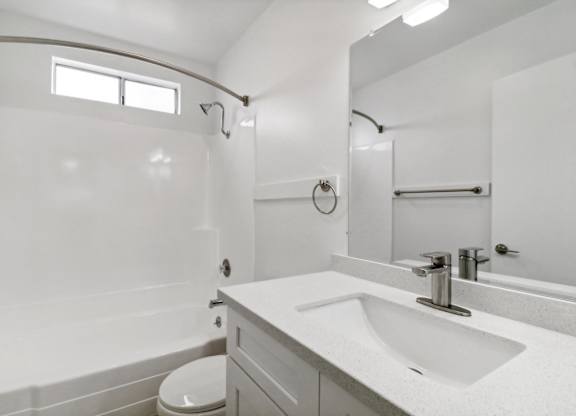 A white bathroom with a toilet, sink, and mirror.