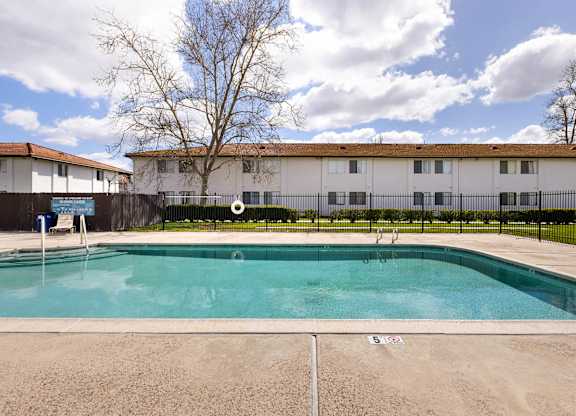 A swimming pool in front of a building with a fence around it.