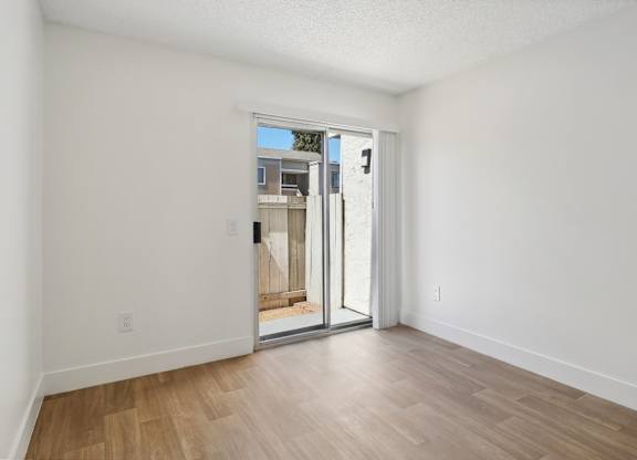 A room with a sliding glass door leading to a balcony.
