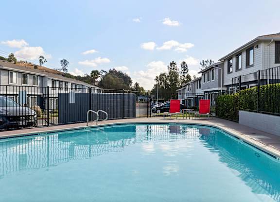 A swimming pool in a residential area with houses and trees in the background.