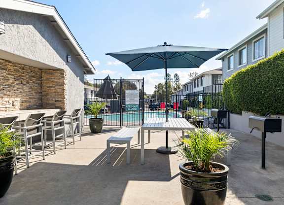 A patio with a table and chairs and a pool in the background.
